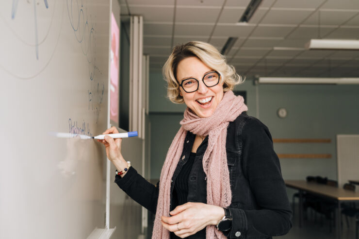 Woman writing on whiteboard, facing the camera