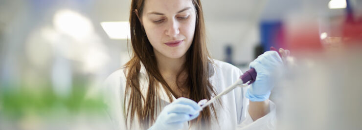 Female science student pipetting in a lab.