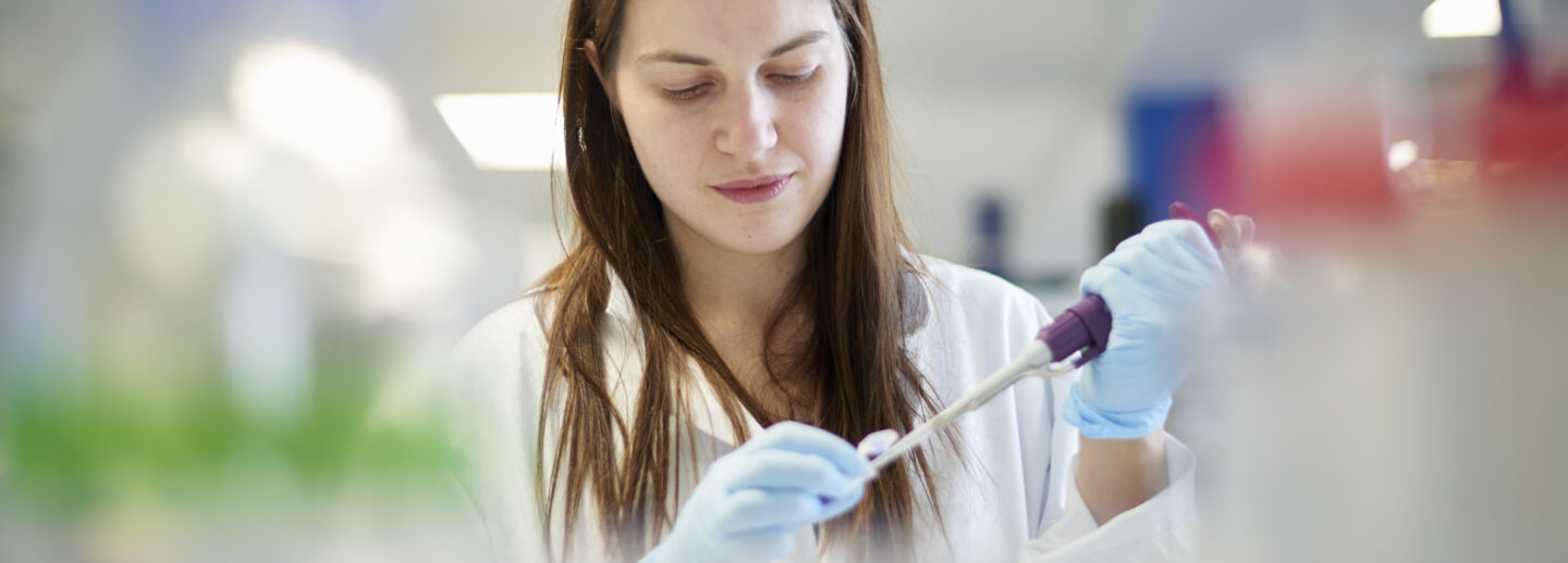Kvinnlig student i ett labb med en pipett.