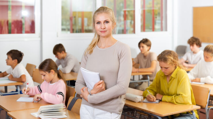 Kvinnlig pedagog håller anteckningar med ett fokuserat uttryck i en skolmiljö