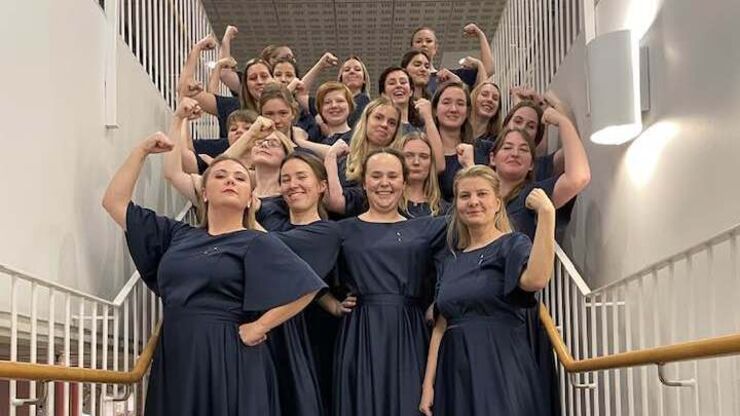 Gruppbild på kören när de spänner musklerna. Bakom kulisserna på kvinnokamps-konserten. 