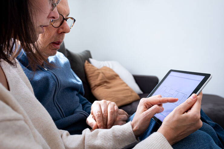 Kvinna visar äldre man hur man använder en läsplatta.