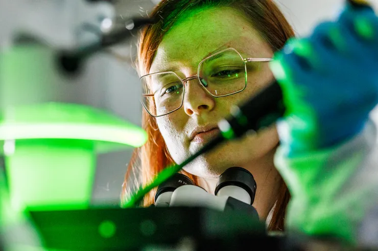 Headshot of a young female reseacher by a microscope.