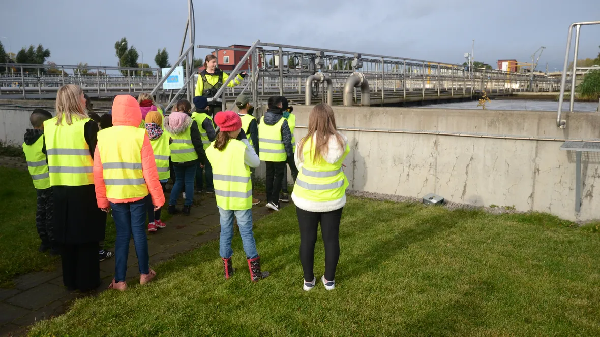 Lärare och elever i gula västar vid ett reningsverk. 
