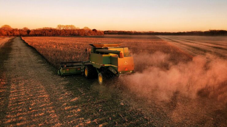 A John Deer combine harvester riding in a field.