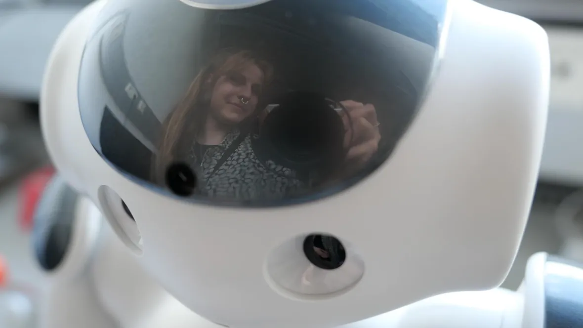 The photographer is reflected in the robot's shiny head