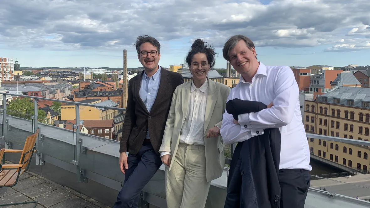 Tre glada personer firar framläggning av doktorsavhandling.