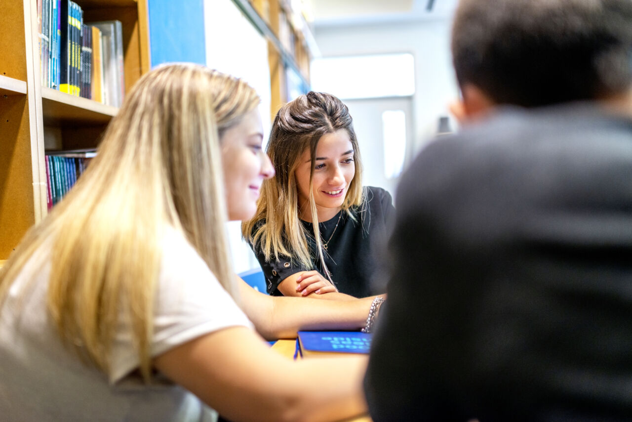 Elever diskuterar i bibliotek