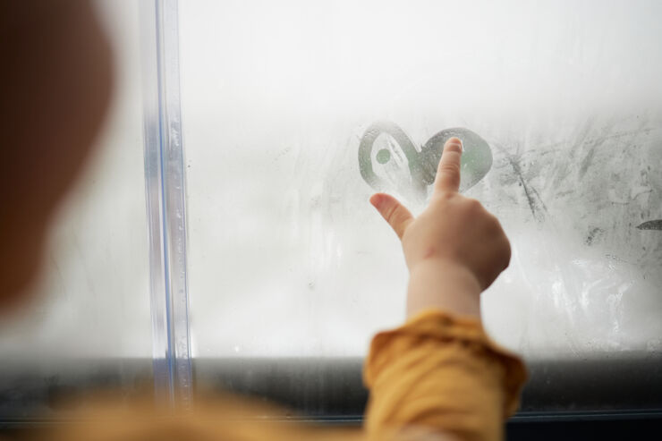 Barnhänder gör ett hjärta på immigt fönster