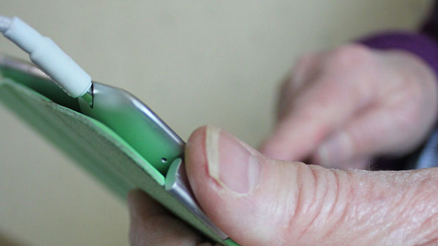 Äldre händer håller i en mobiltelefon