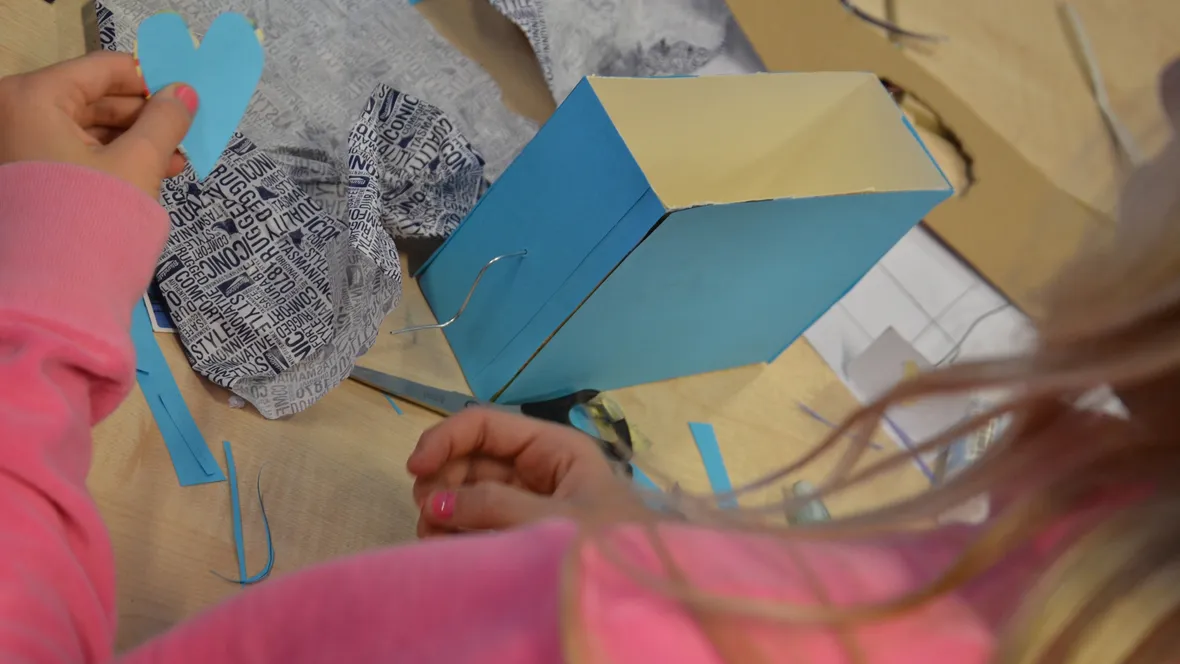 Händer som arbetar med en blå kartong. 