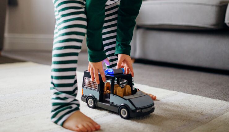 Barns ben, armar som sträcker sig efter leksakspolisbil