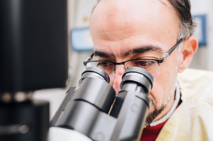 A man using a microscope in a lab.