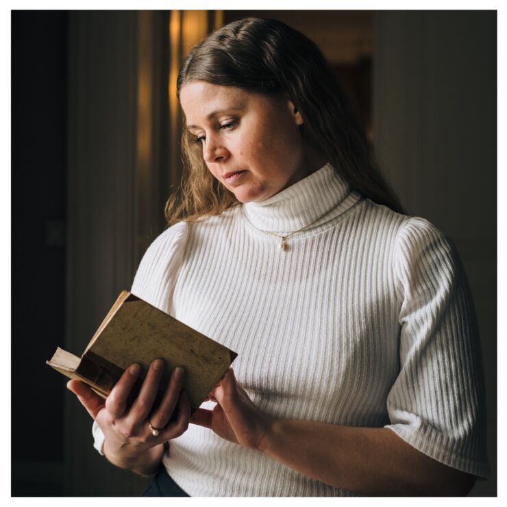 Episode guest Johanna Vernqvist is standing reading a book.