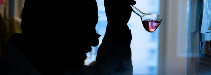 A man sits and analyzes a sample in a beaker.