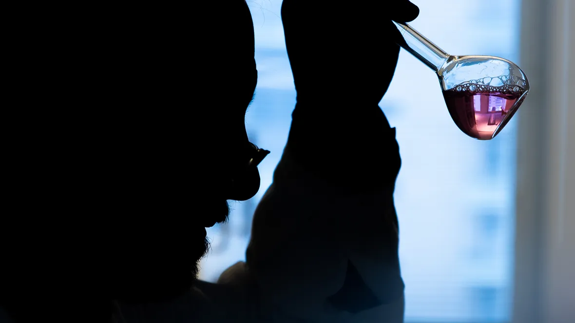 En man sitter och analyserar ett prov i en bägare.