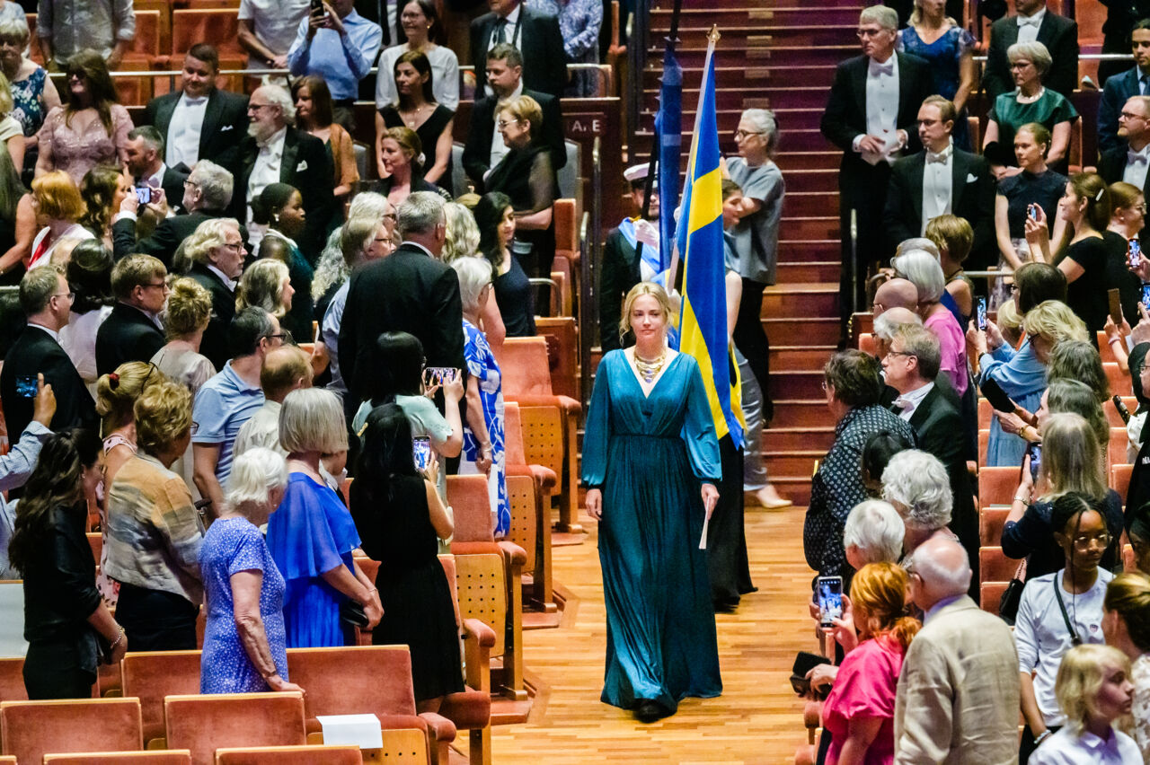Procession passerar genom festklädd publik