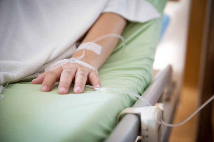 Hand with IV on bed.