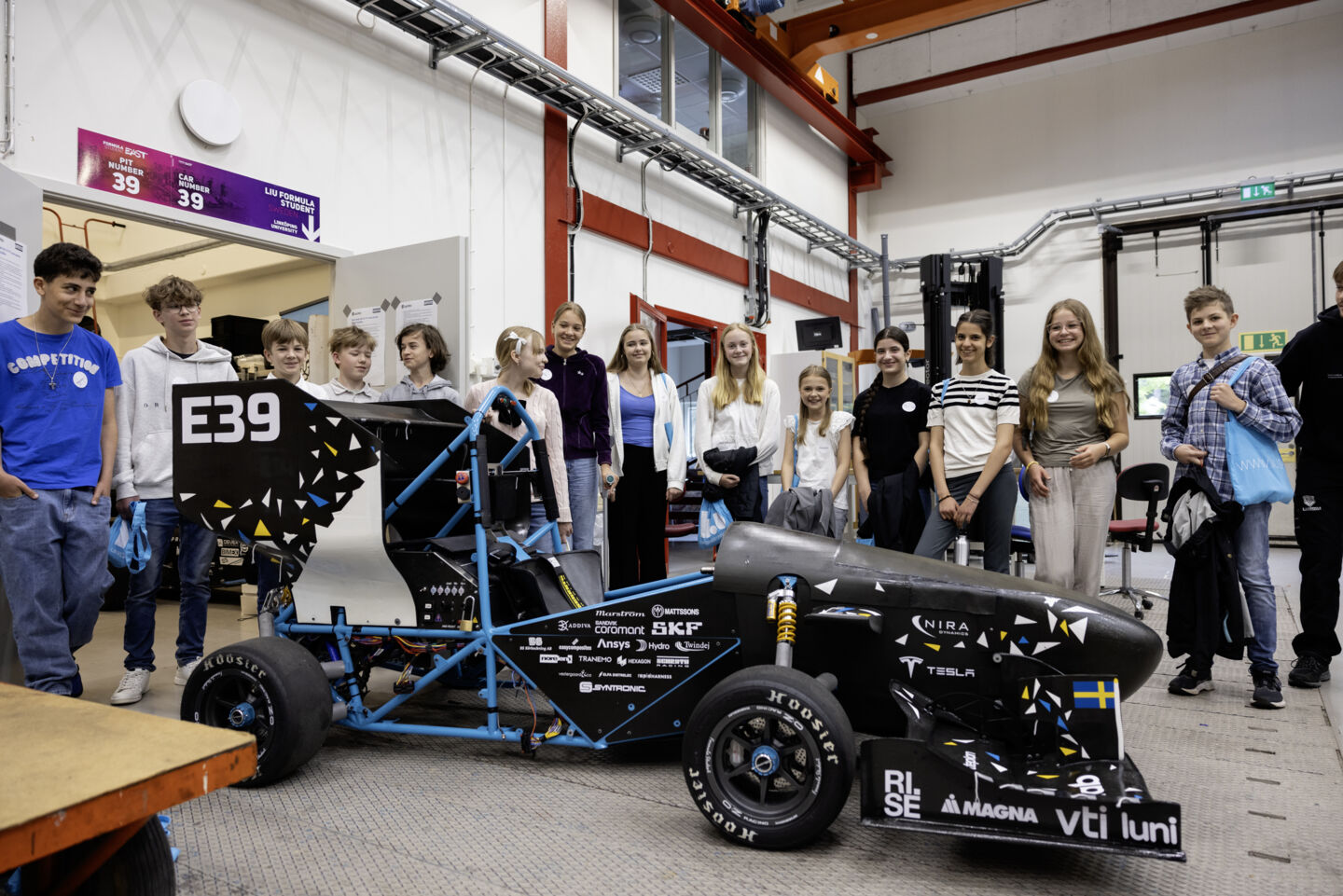 Bild på en grupp deltagare vid en Formula bil under Sommarveckan 2024