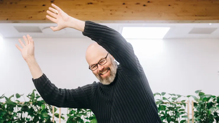 Person (Erik Berglund) står vid datorn och sträcker upp armarna.