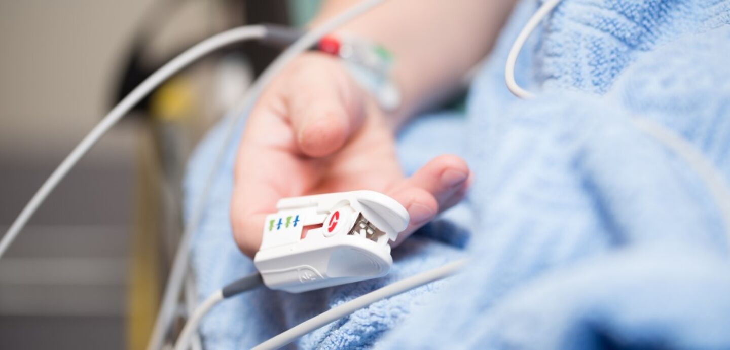 Närbild på en patient i en sjukhussängs hand.