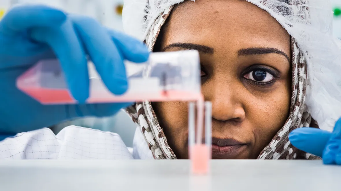 Closeup of a woman pouring a chemical into a test tube