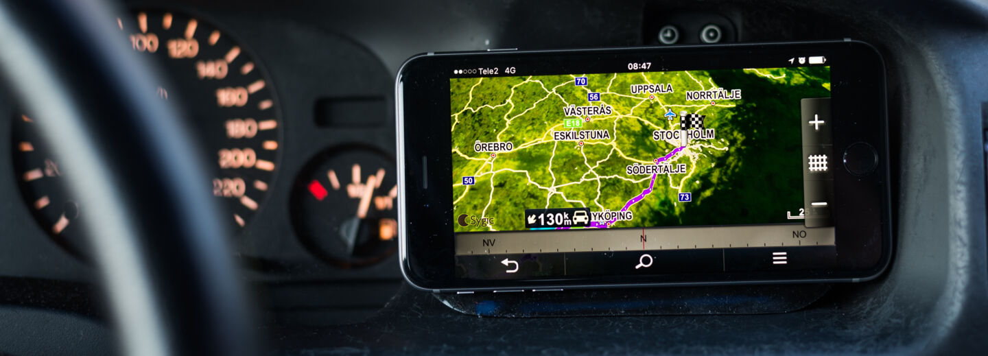 Cellphone with map view next to the steering wheel of a car