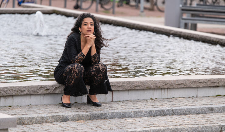 Athena Farrokhzad sitter vid en fontän på Campus Valla.