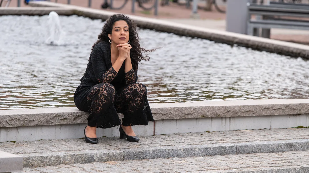 Athena Farrokhzad sitter vid en fontän på Campus Valla.