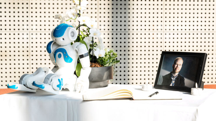 Kondoleansbord med robot, foto och bok.