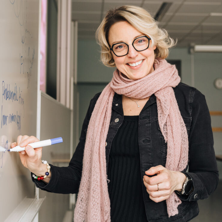 Avsnittsgäst Helene Winzell står vid whiteboard och skriver.