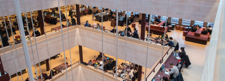 Four floors in a large building. At every floor, there are people sitting reading and using computers.