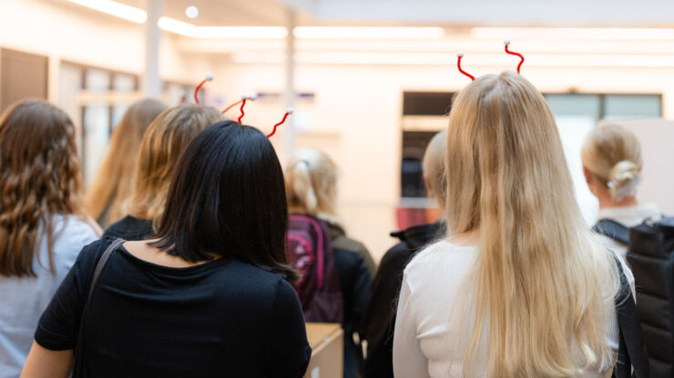 En grupp nya studenter fotade bakifrån, flera med diadem av piprensare och flirtkulor i håret.