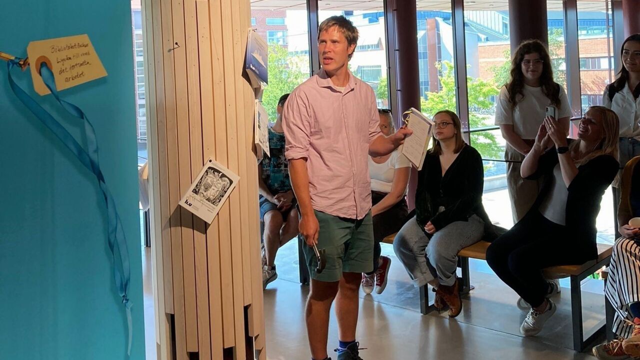 En man som ska ta doktorseksamen presenterar sin avhandling. 