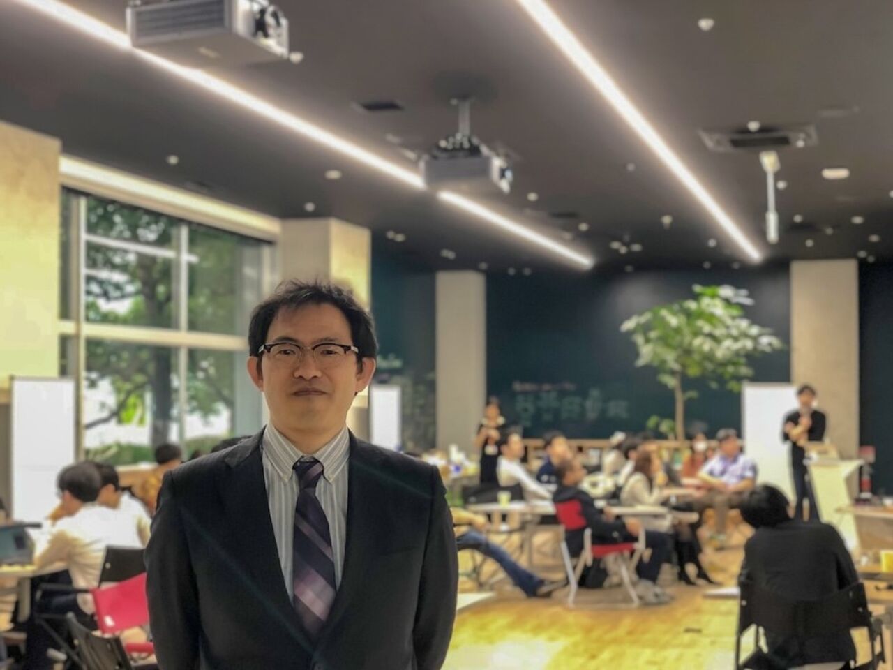 Porträtt av man framför grupp av människor