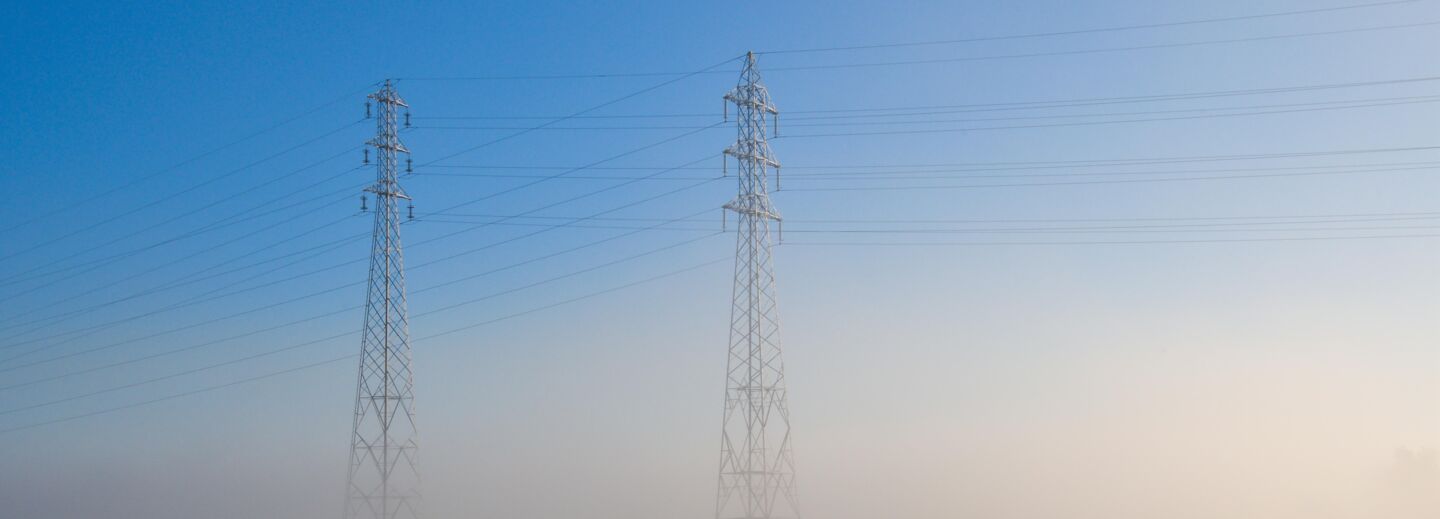 Powerlines at foggy field. 