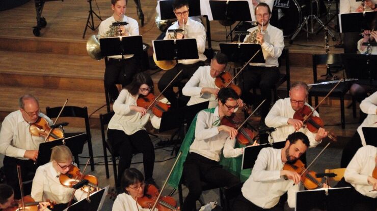 Orkestern är klädd i cape och lutar sig när de spelar