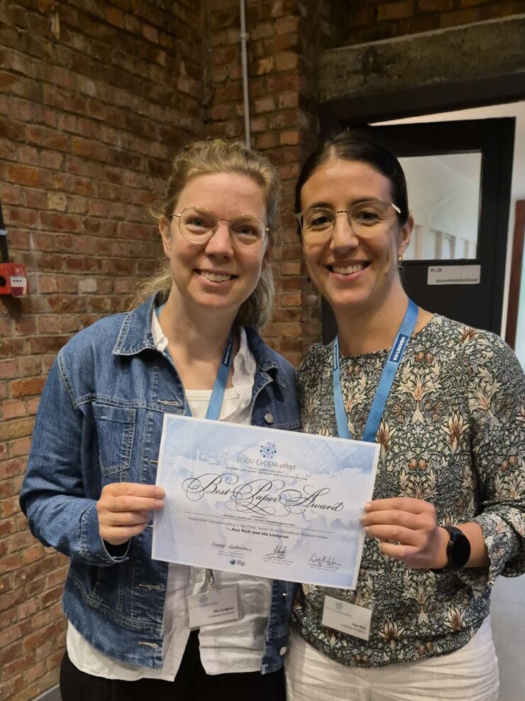 Two happy female smiling at camera and holding a diploma in hand. 