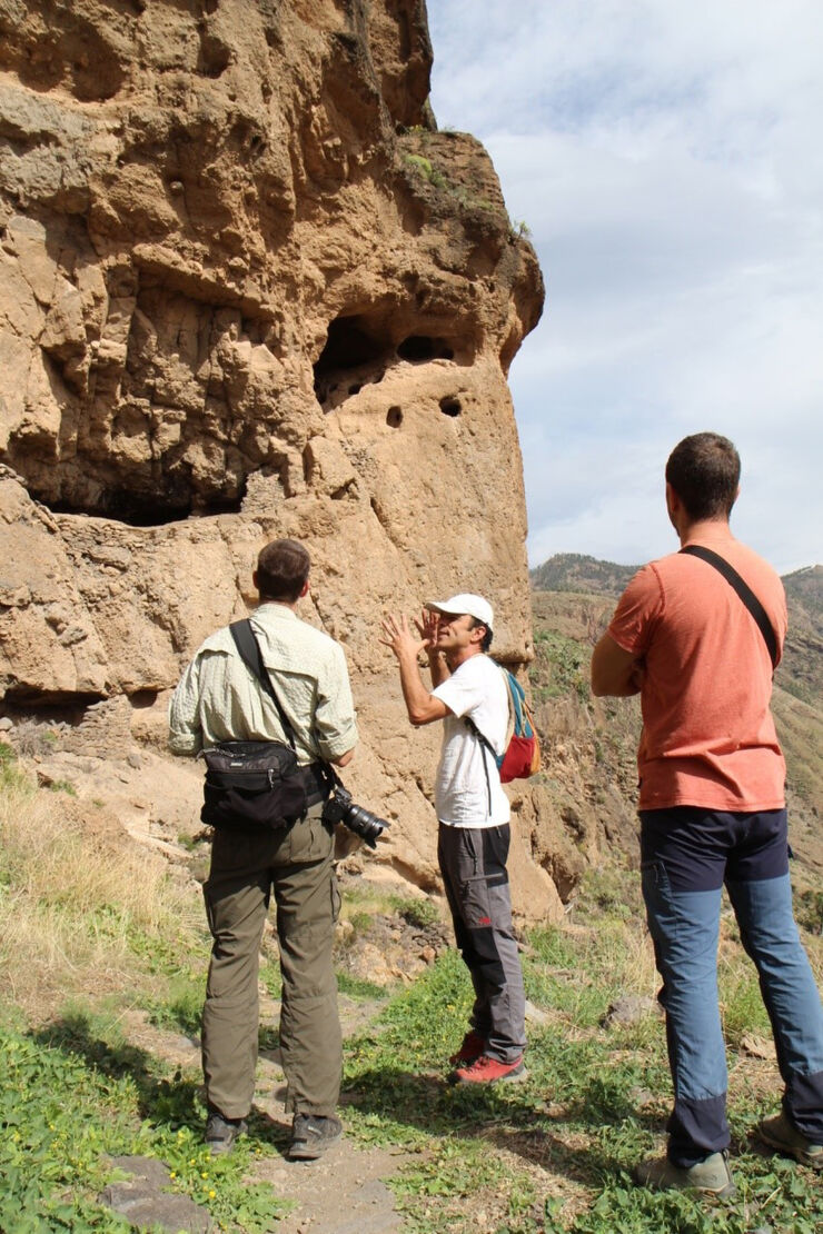 Three men looking up at holes in the mountain side at Gran Canaria.