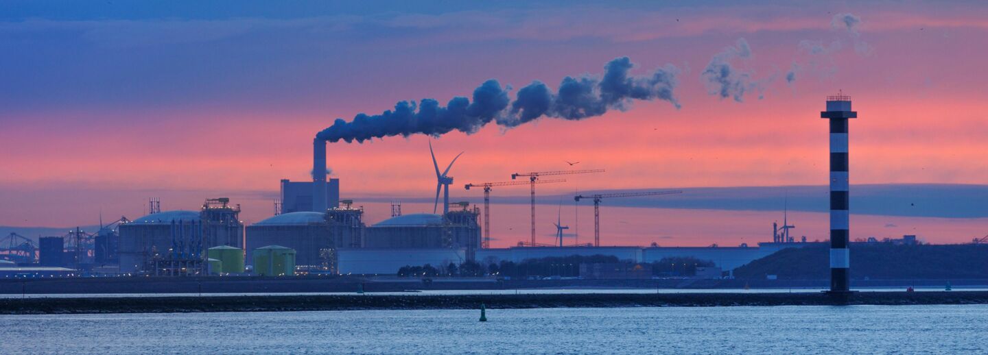 Industrial buildings by the water under pink and blue skies