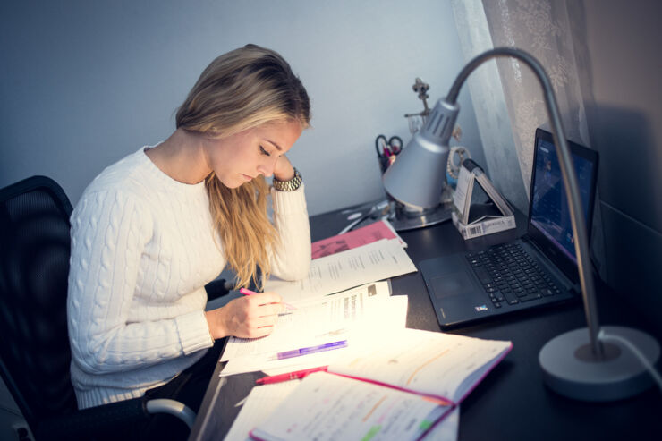 Student sitter vid sitt skrivbord och pluggar