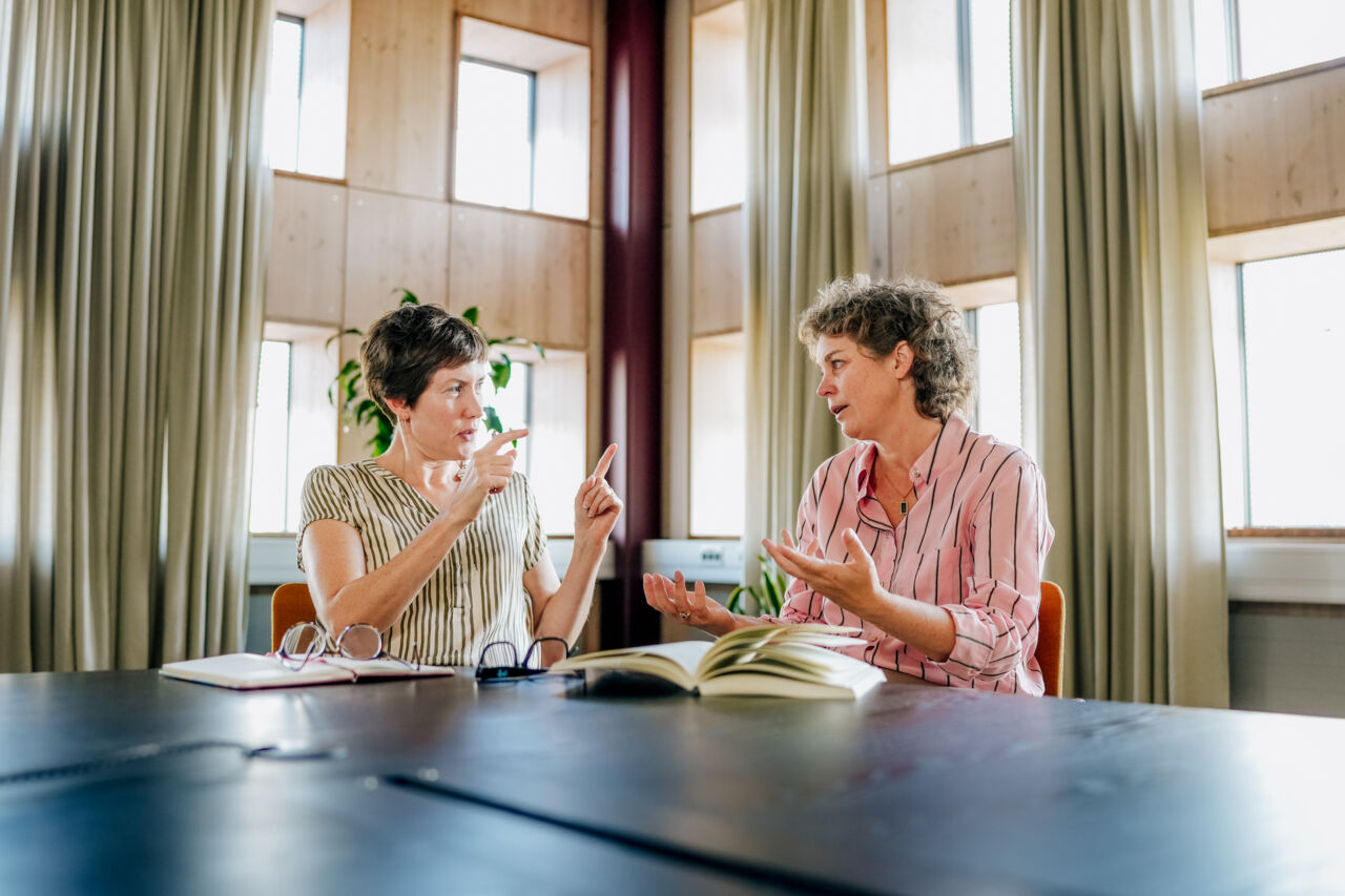 Två kvinnor sitter vid ett bord och samtalar.