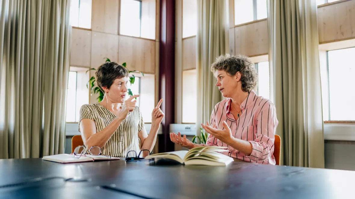 Two women sitting at a table talking.