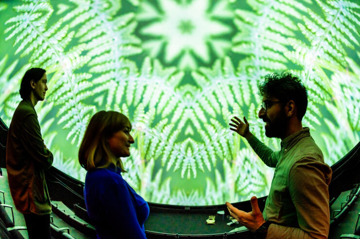 Three people standing in front of a projection in a dome theatre