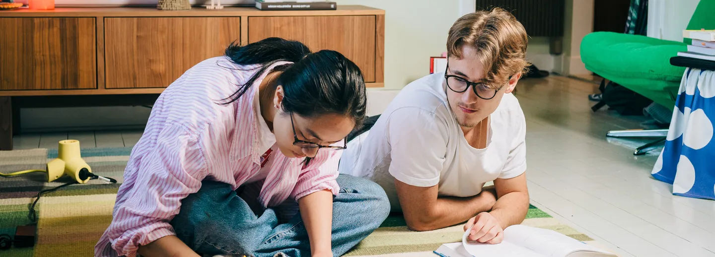 A female and a male student studying on the floor