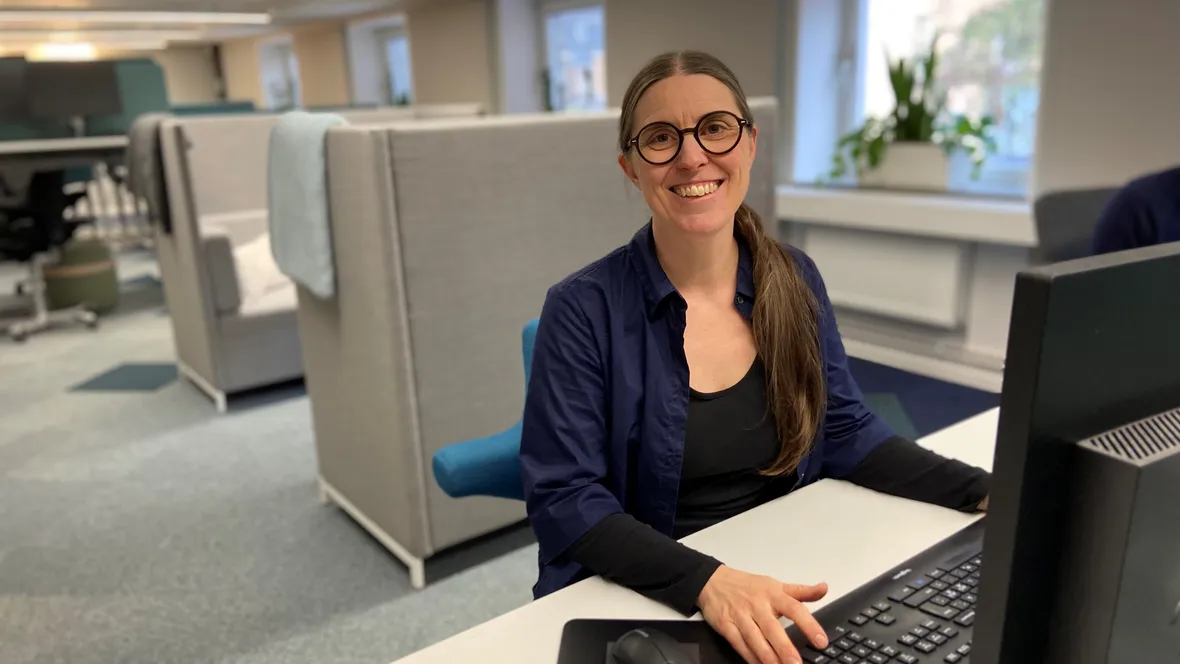 Kvinna vid skrivbord framför dator.