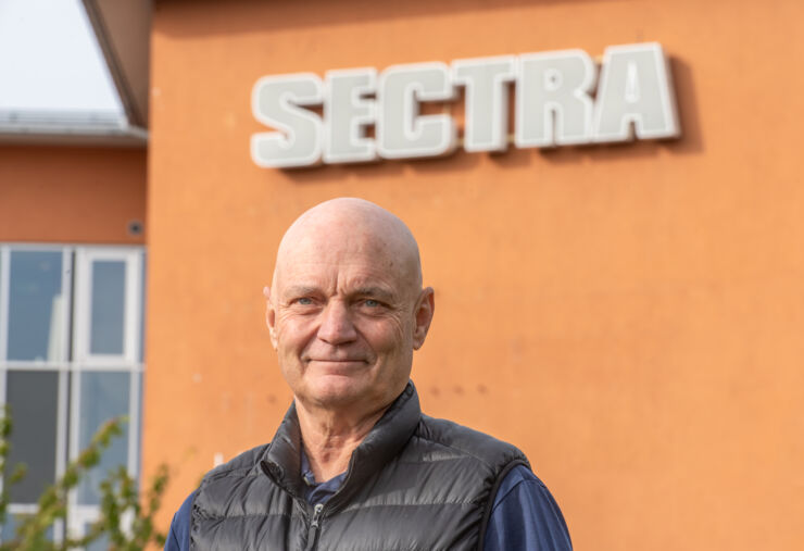 Portrait of a man (Torbjörn Kronander) in front of a building with Sectra written on it