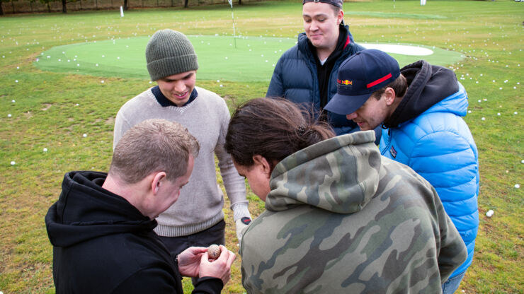 Studenter och teknikern studerar en av golfbollarna. 