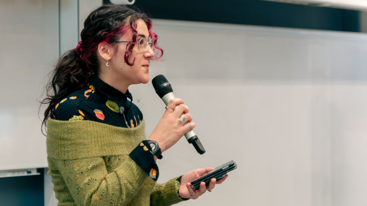 woman in green sweater and a ponytail talking into microphone.