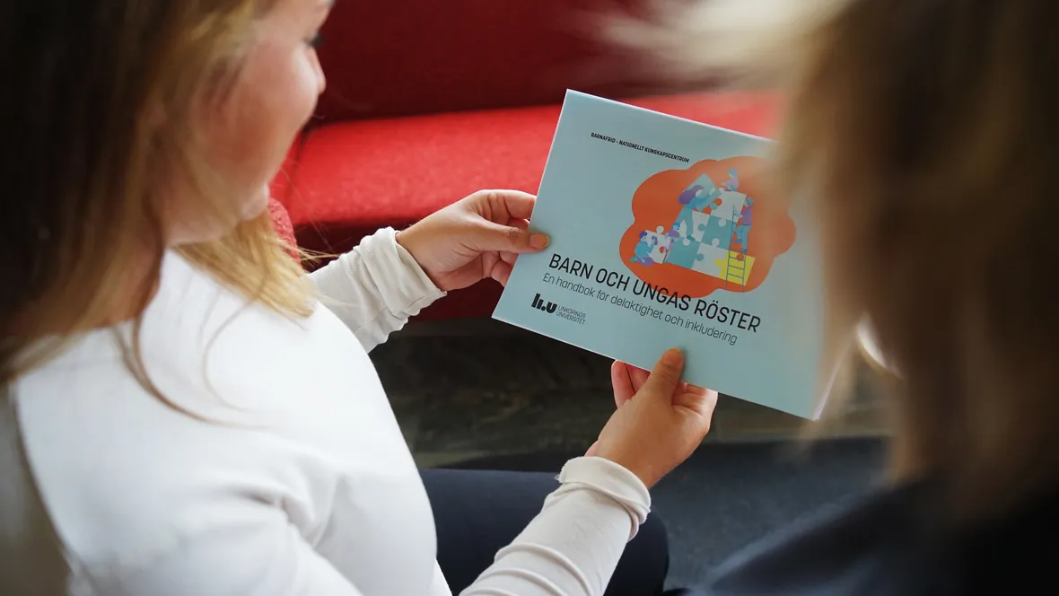 Över axeln-perspektiv på en kvinna som håller i handboken Barn och ungas röster.